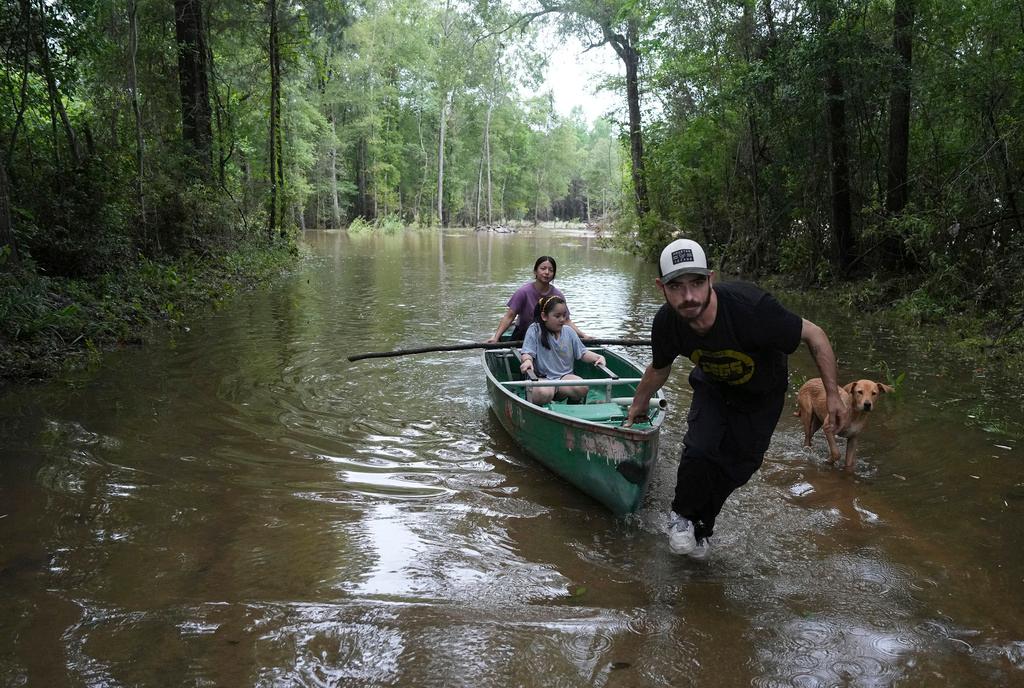 Alvaro Trevino pulls a canoe with Jennifer Tellez and Ailyn, 8, after they checked on their home on Sunday, May 5, 2024, in Spendora, Texas.