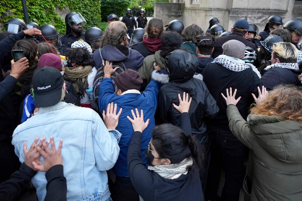 Pro-Palestinian protesters support the positions held by others as University of Chicago police officers reposition a barricade keeping protesters from the university's quad 