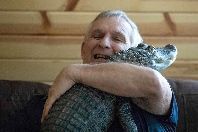 Joie Henney hugs his emotional support alligator named Wally
