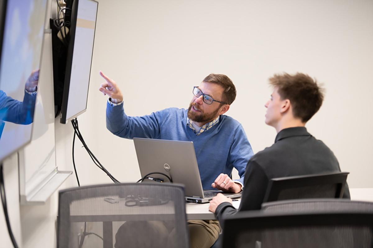 In a classroom at Cedarville University, Dr. George Landon works one-on-one with a computer science student.  