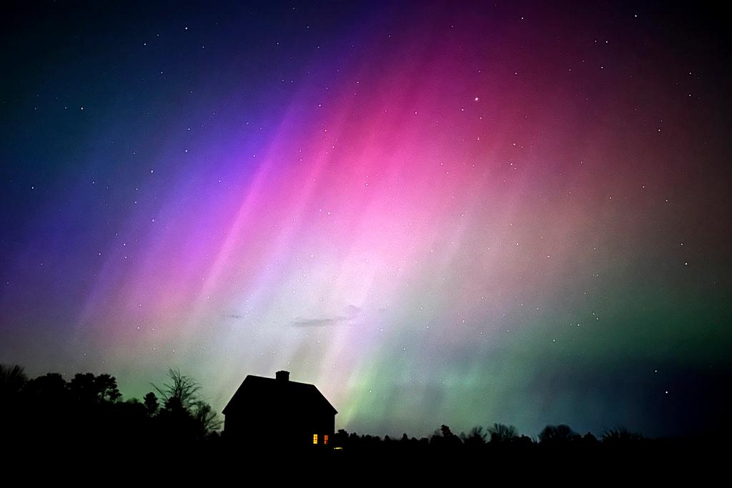 Northern lights flare in the sky over a farmhouse, late Friday, in Brunswick, Maine