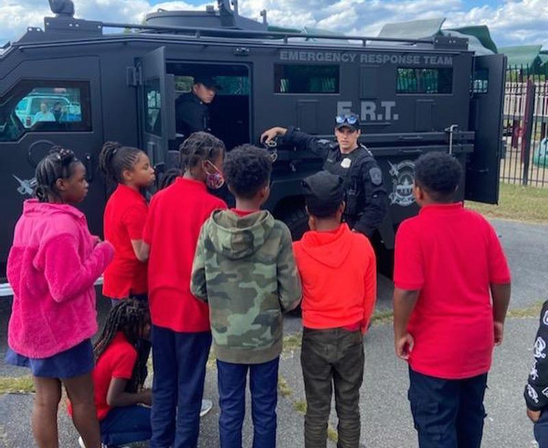 Kids with red t-shirts surrounding a Police SWAT vehicle
