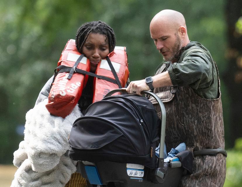 A woman is handed her child after being evacuated by boat from her homes with the help of deputies with the Montgomery County Sheriff's Office in Conroe, Texas