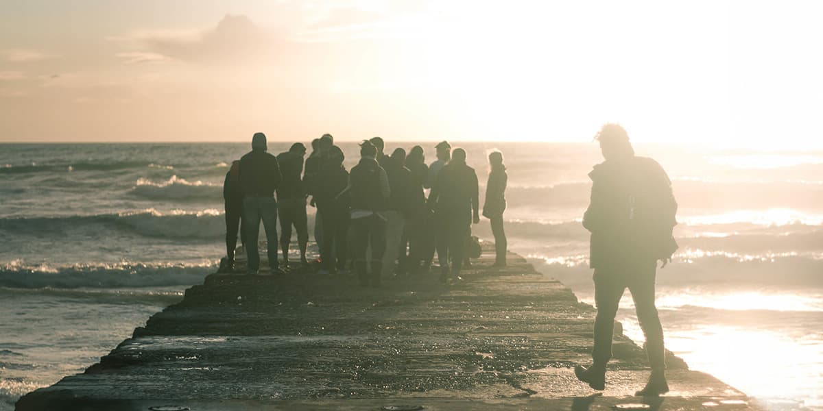 Person walking up to group standing at end of dock at twilight