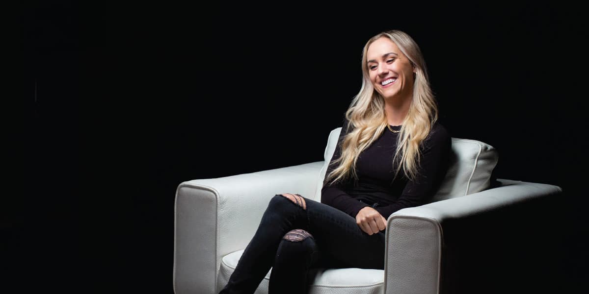 woman in black sitting in white chair on black background