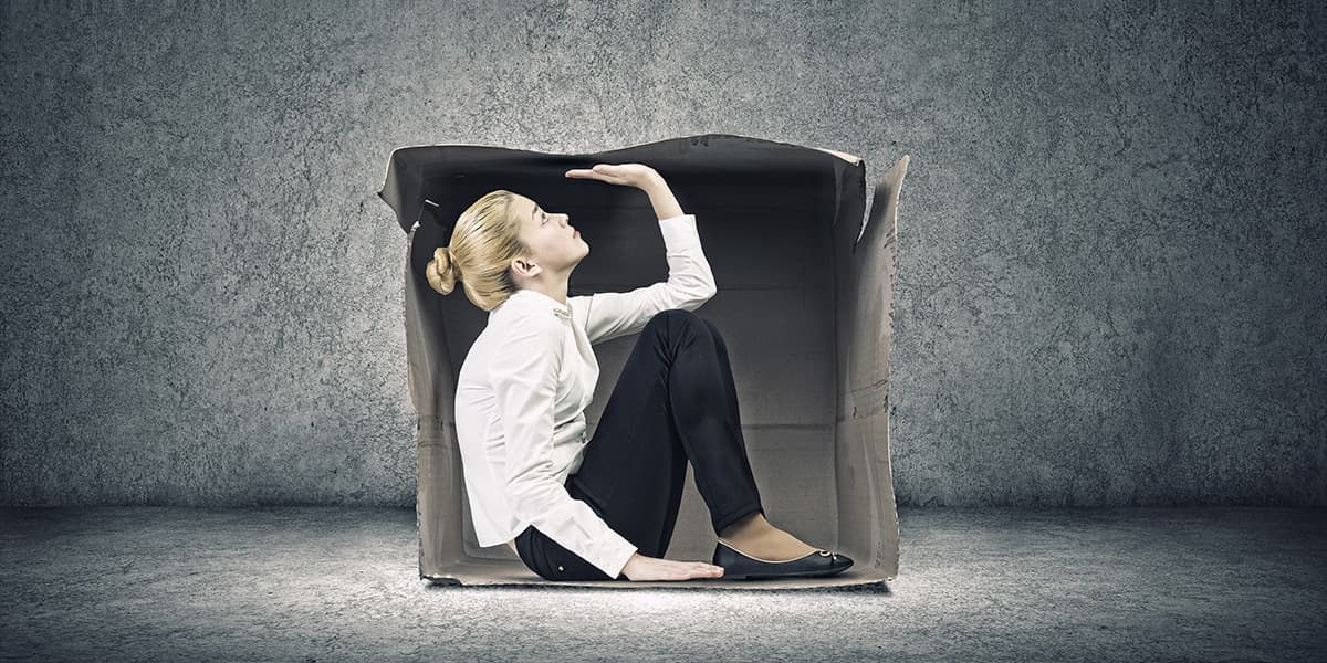 Woman sitting in cardboard box in concrete room