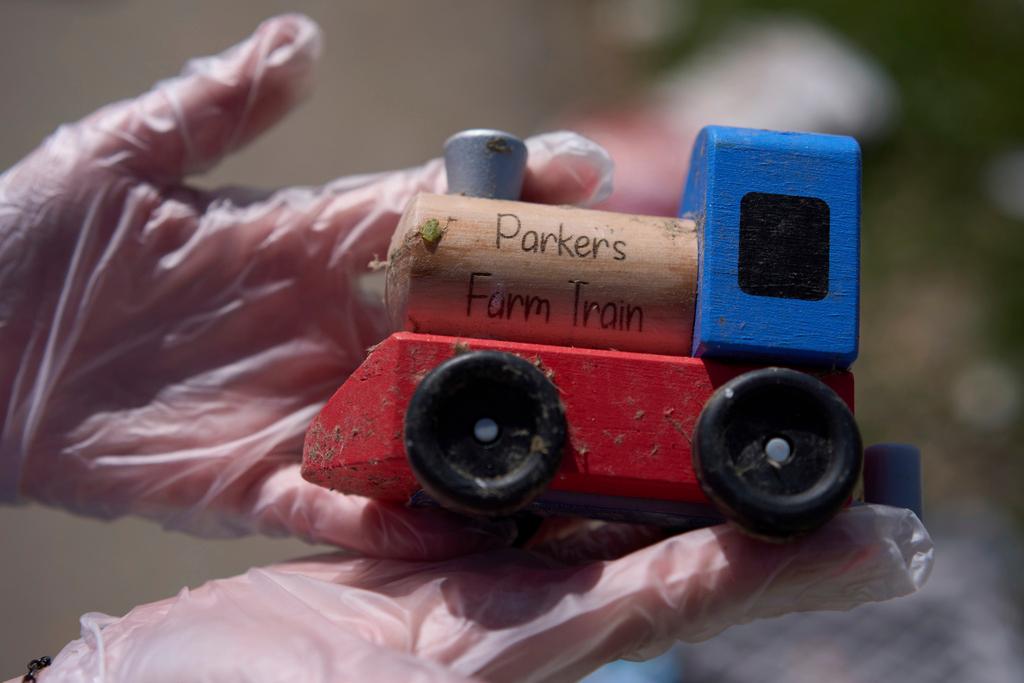 A resident holds her grandson's tory train as she looks for salvageable items of her daughter's destroyed home