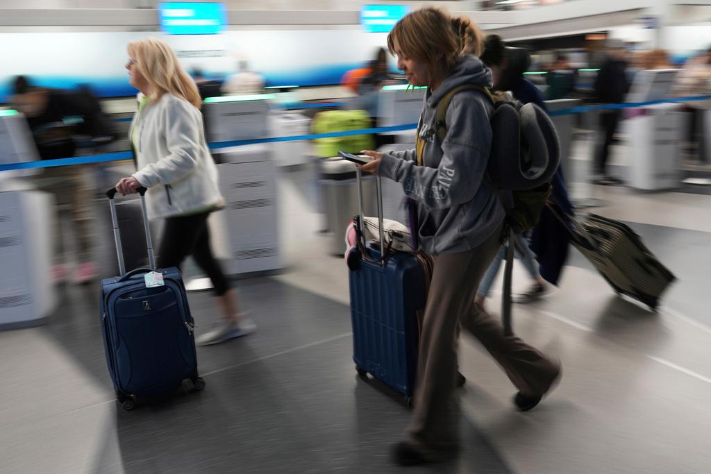 Travelers walk with their luggage through at O'Hare International Airport in Chicago