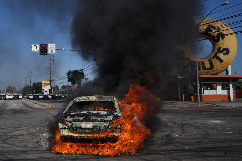 A car burns during a protest in Compton, Calif. after federal immigration authorities conducted operations.