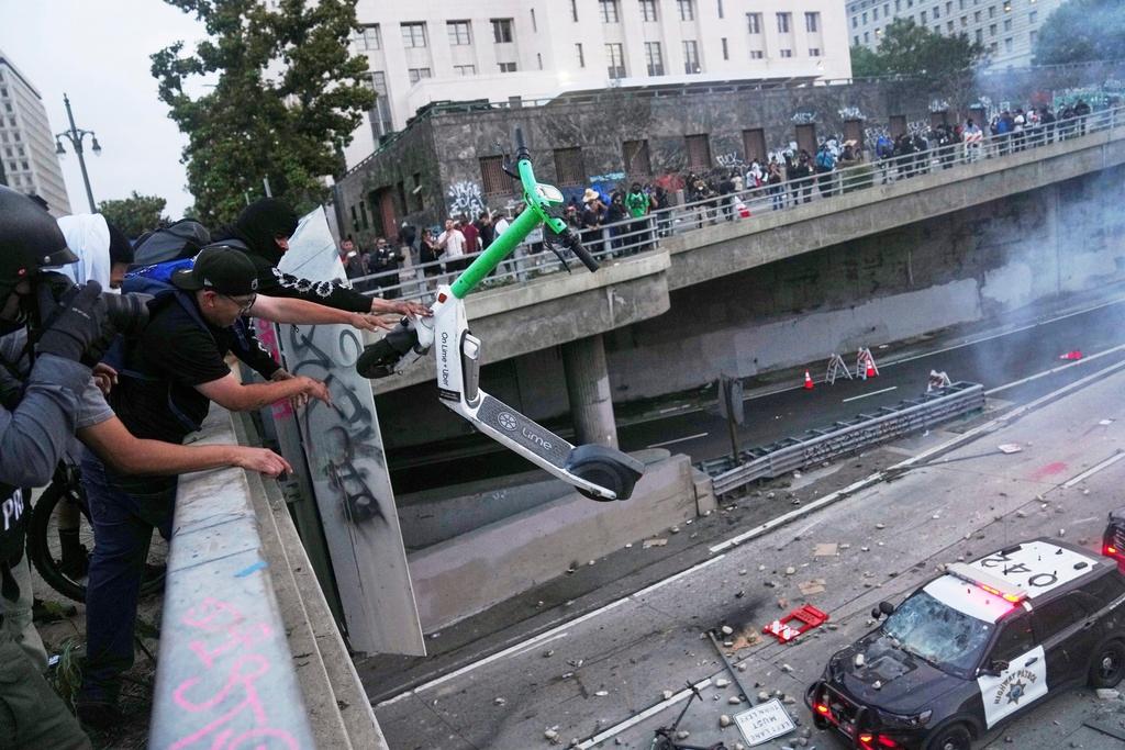 A protester throws a scooter at a police vehicle near the metropolitan detention center of downtown Los Angeles
