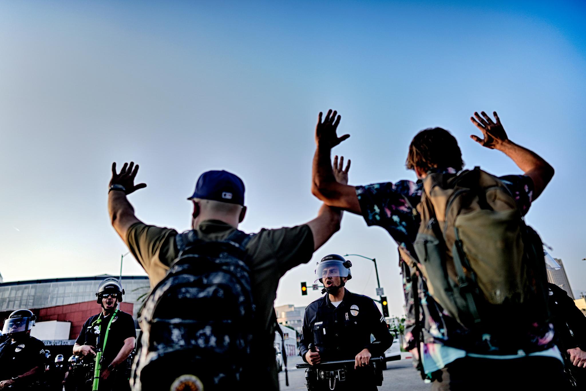 Two men holding their hands up in front of law enforcement