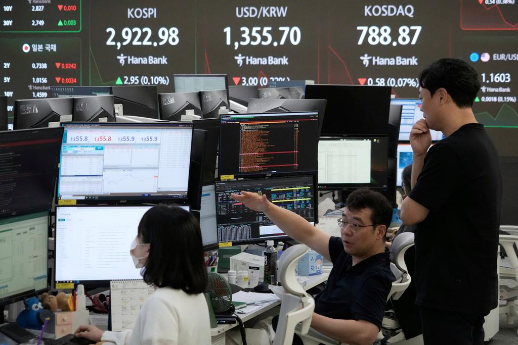 Currency traders work near a screen showing the Korea Composite Stock Price Index (KOSPI), top left, and the foreign exchange rate between U.S. dollar and South Korean won, top center, at the foreign exchange dealing room of the KEB Hana Bank headquarters in Seoul, South Korea