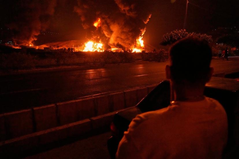 A man looks at flames rising from an oil storage facility after it appeared to have been struck by an Israeli strike in Tehran, Iran