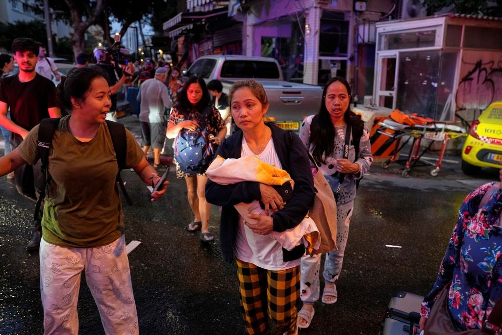 A woman holds her baby as residents evacuate the area after a missile launched from Iran struck in downtown Tel Aviv