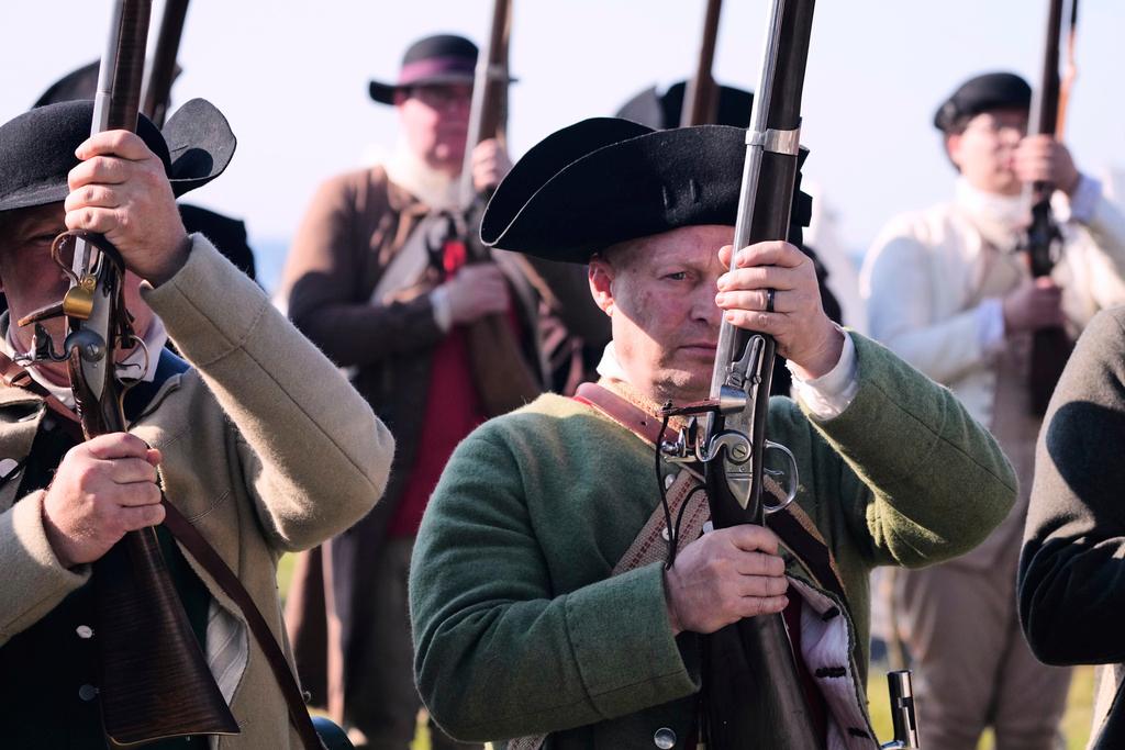 Chris Silver, right, of Celina, Ohio, prepares to face the British during a reenactment in celebration of the 250th anniversary of the Battle of Bunker Hill