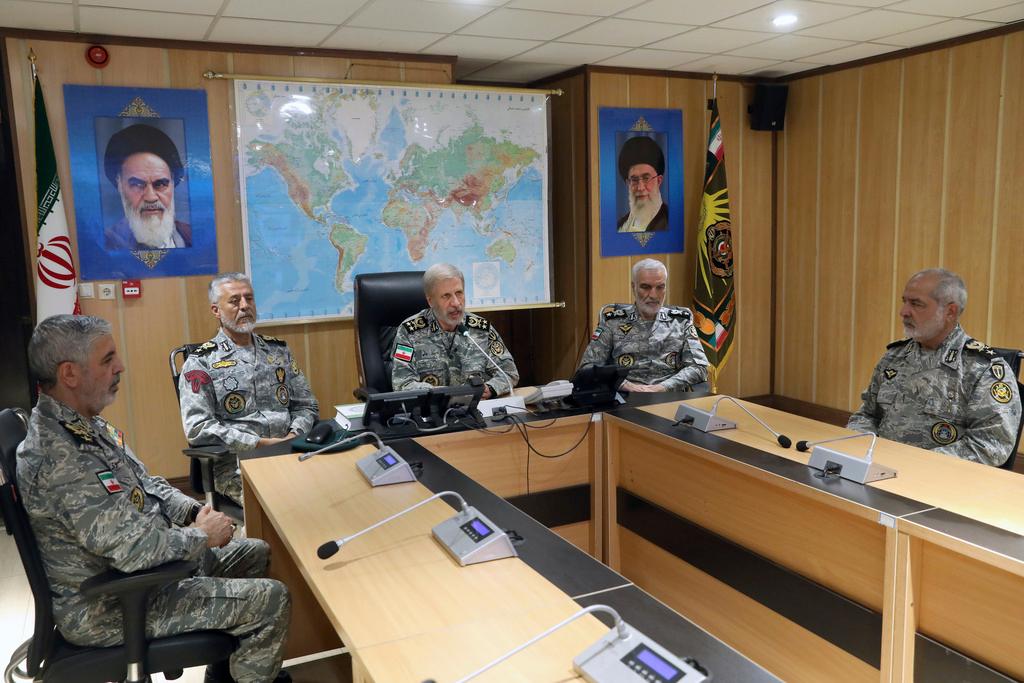Iran's army commander-in-chief Gen. Amir Hatami, center, accompanied by high ranked army commanders, speaks in a video call with top commanders of the army, in Zolfaghar central headquarters, Iran, as portraits of the late revolutionary founder Ayatollah Khomeini, left, and Supreme Leader Ayatollah Ali Khamenei hang on the wall.