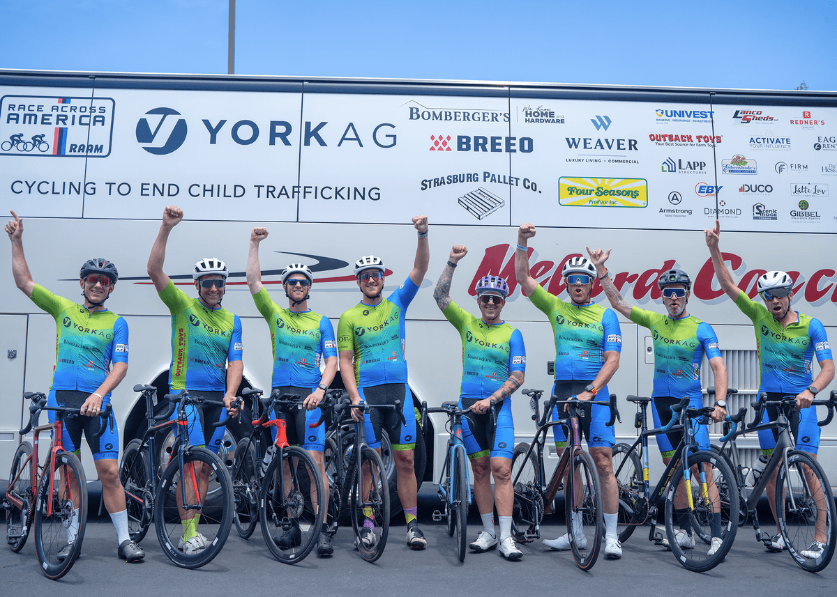 8 cyclists holding their fists into the air, with the other hand steadying the bicycles that just carried them to first place 