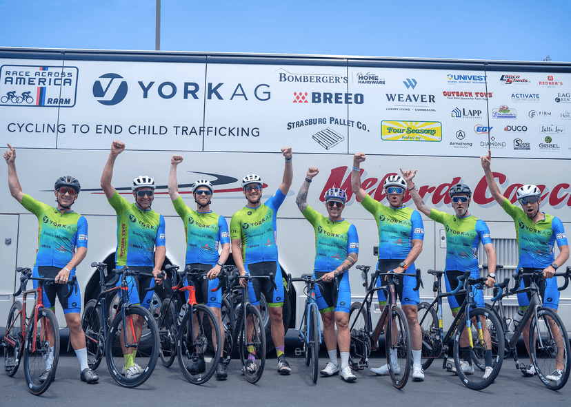 8 cyclists holding their fists into the air, with the other hand steadying the bicycles that just carried them to first place 
