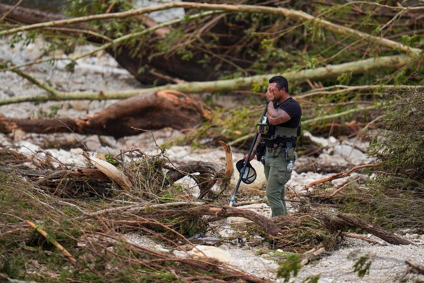 A Sheriff's deputy pauses while combing through the banks of the Guadalupe River near Camp Mystic
