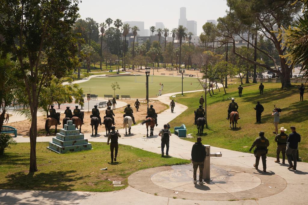Federal agents ride on horseback at MacArthur Park in Los Angeles. Their uniforms read "Police U.S. Border Patrol," and "HSI," which stands for Homeland Security Investigations