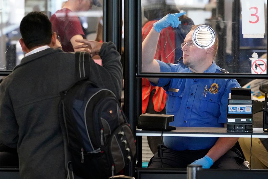 A Transportation Security Administration agent signals for the next airline passenger in line at a security checkpoint in Chicago's O'Hare International Airport