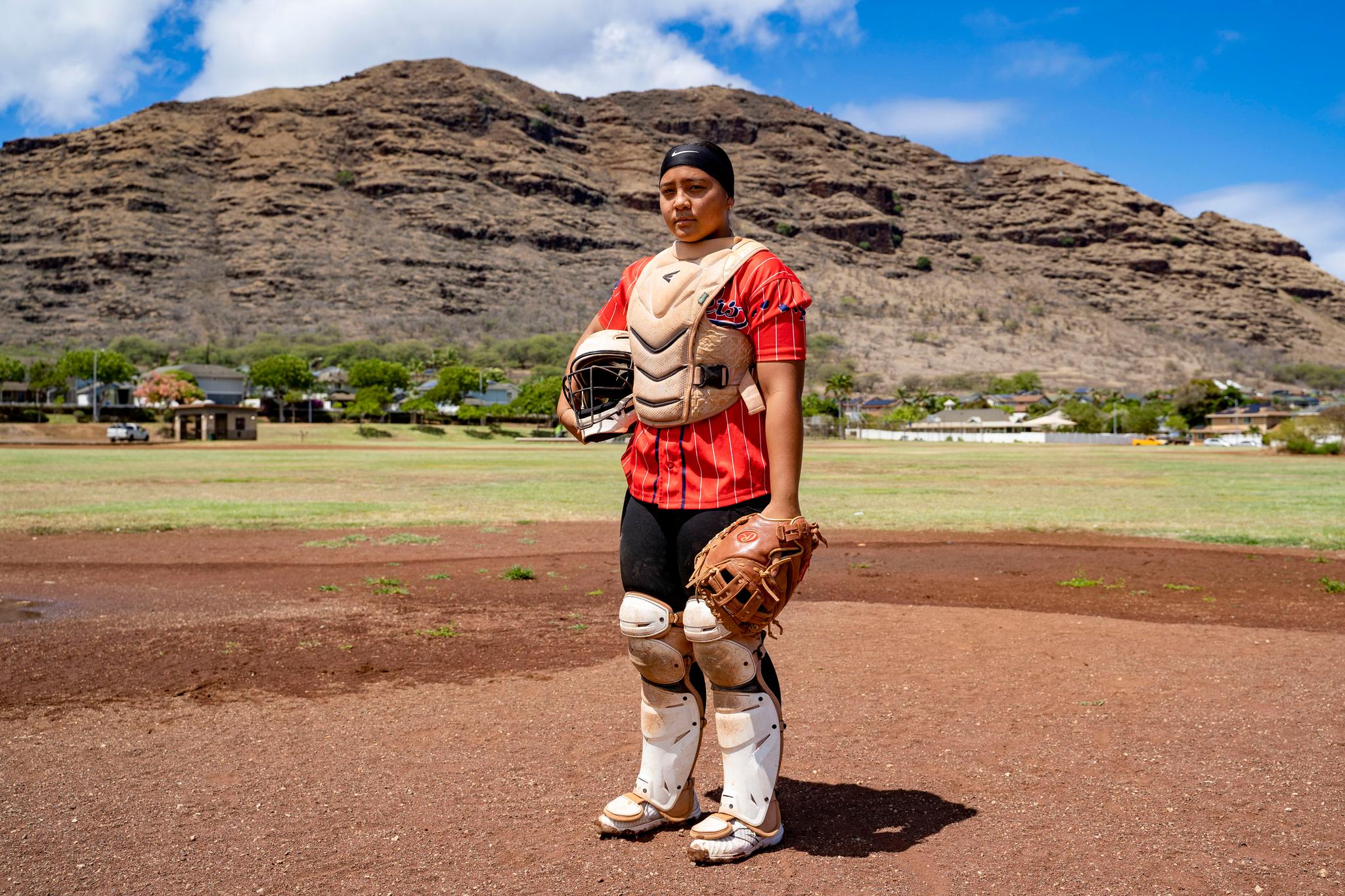 Young woman dressed in a baseball catcher's uniform with a baseball glove