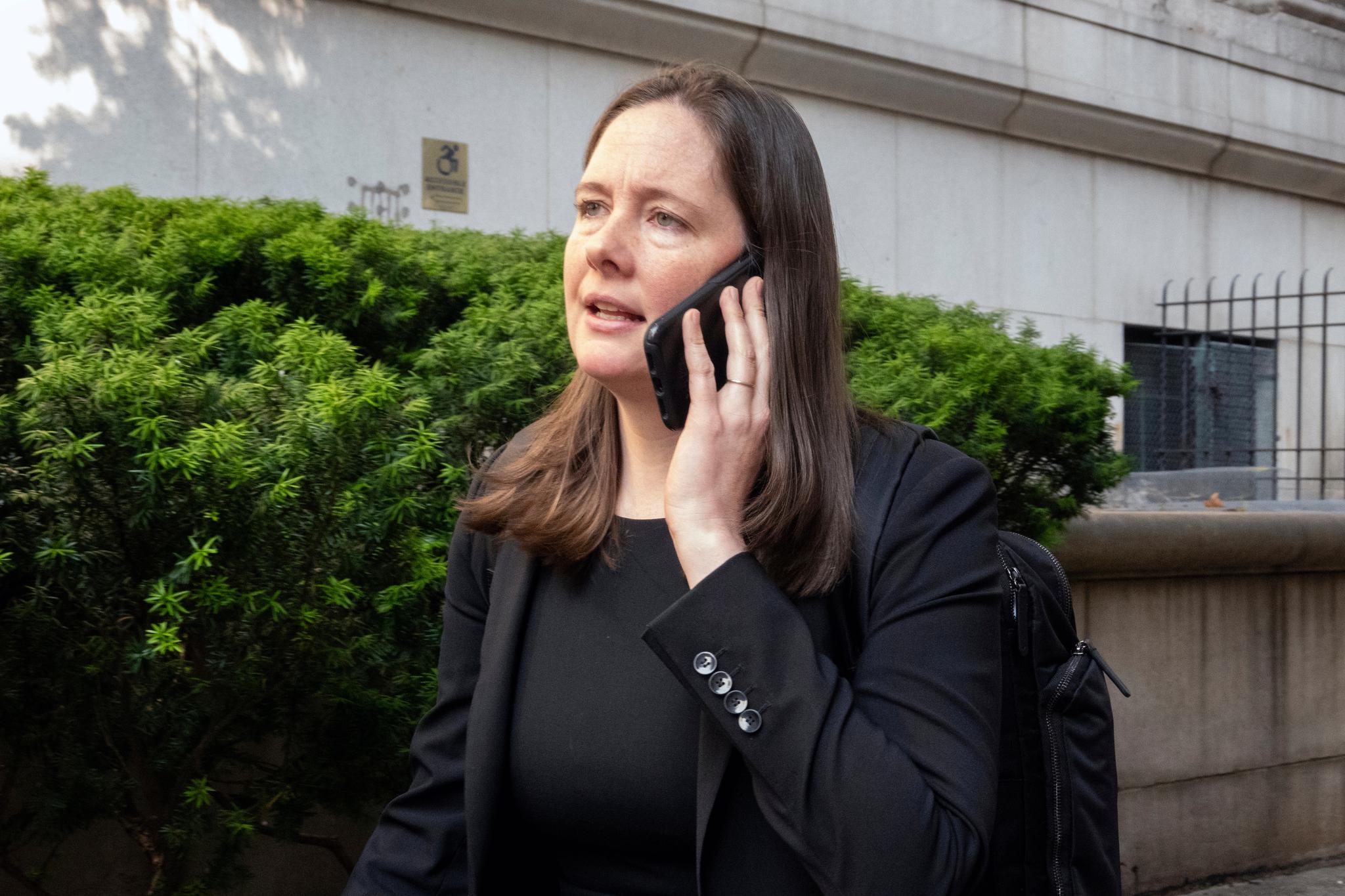 Woman in black suit talking on phone.