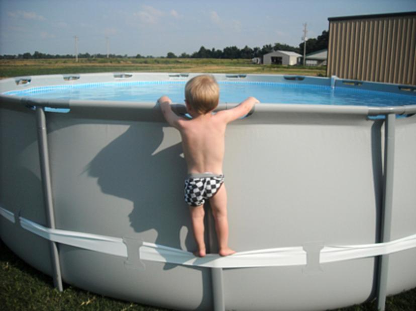 Toddler using side strap to get into above-ground pool.