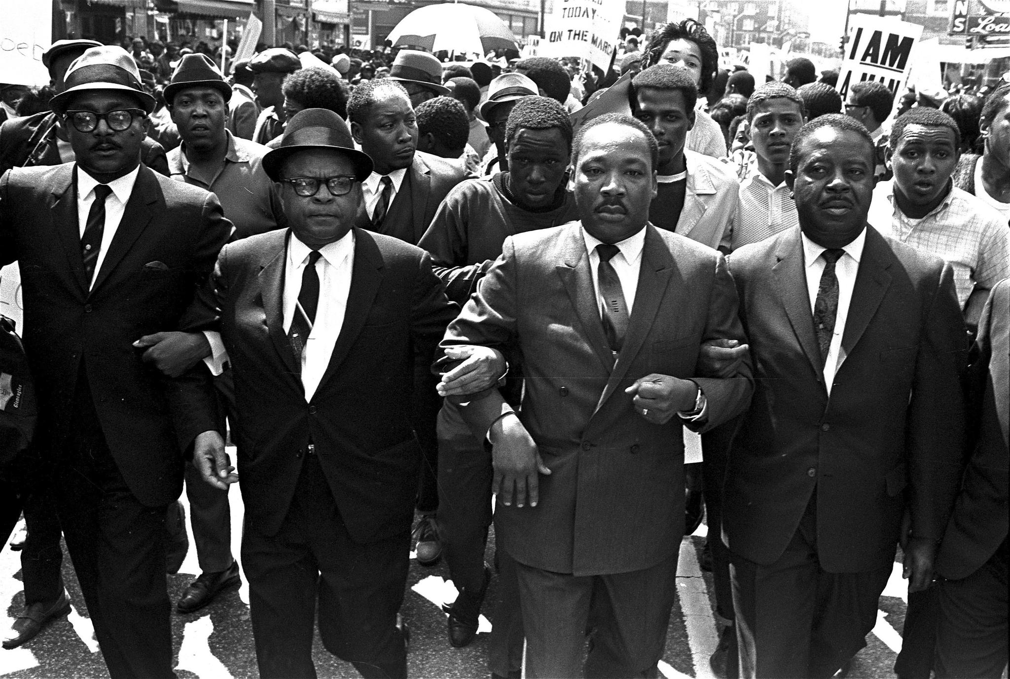 Dr. Martin Luther King, Jr. surrounded by other men in suits, marching