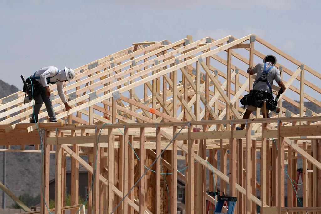 Construction workers frame up a roof of wood lumber at a new home build in Laveen, Ariz. 