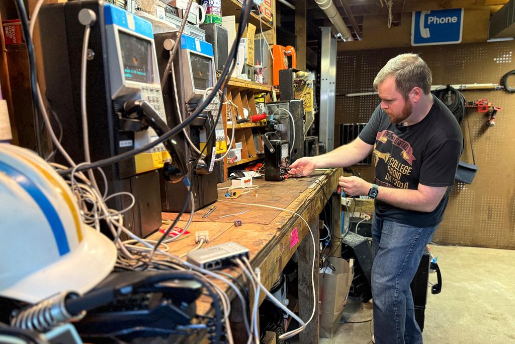 Patrick Schlott repairs an old payphone in his basement workshop in Williamstown, Vt.