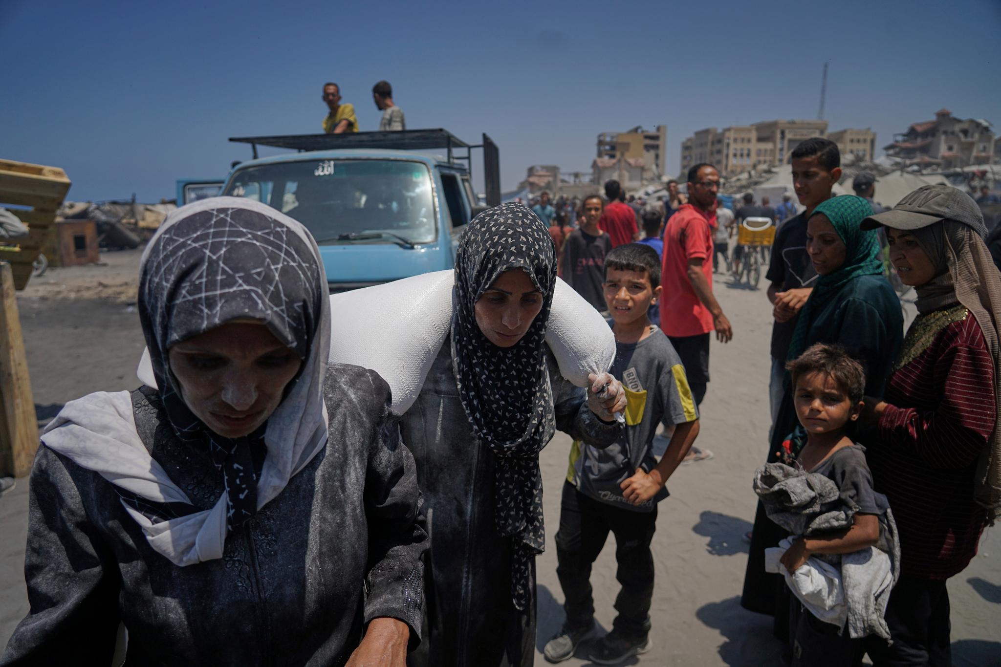 Palestinian families travel by foot, carrying their belongings.