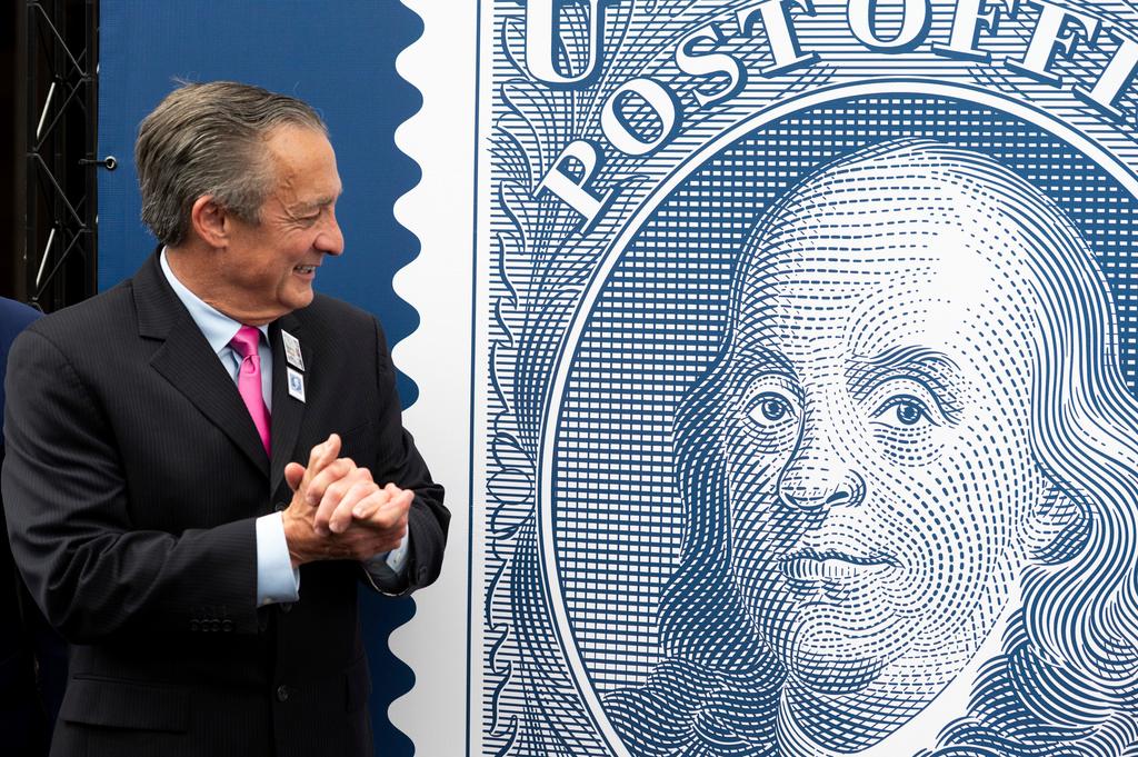 Postmaster General David Steiner looks at a just unveiled Benjamin Franklin stamp to mark the 250th anniversary of postal service's founding