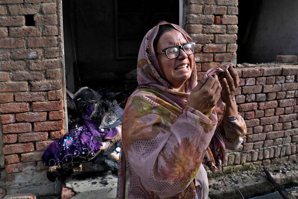 A Christian woman weeps after looking at her home vandalized by an angry Muslim mob
