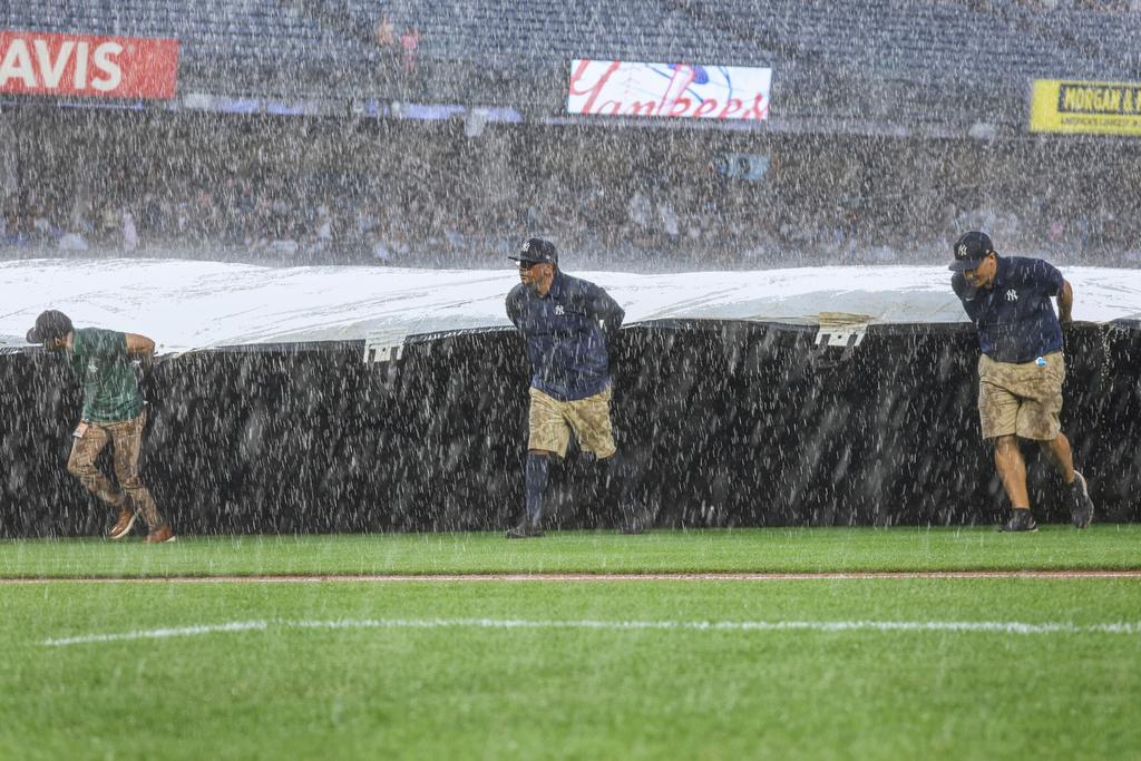 The Grounds crew roll out the tarp during a rain delay in the fifth inning of a baseball game between the New York Yankees and the Tampa Bay Rays,