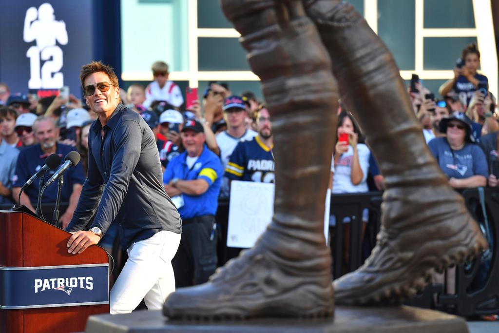 Former New England Patriots quarterback Tom Brady, left, looks at a bronze statue of himself after it was unveiled in Patriot Place Plaza before an NFL preseason football game between the Washington Commanders and the New England Patriots 