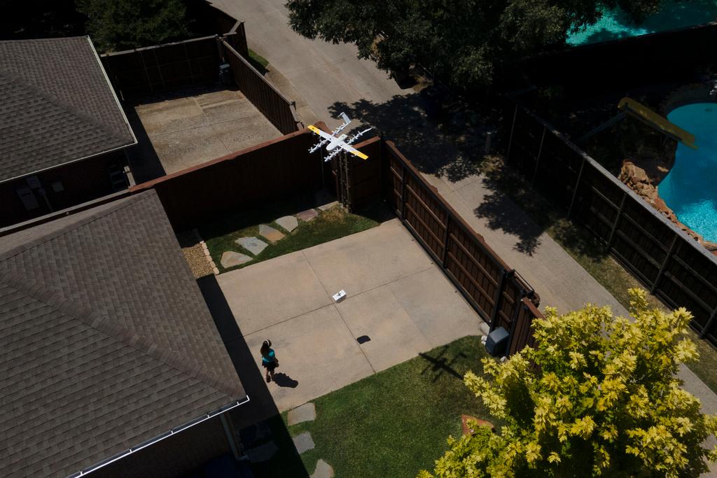 Julep Toth, 9, looks at a drone as it arrives at her house with a delivery in Frisco, Texas
