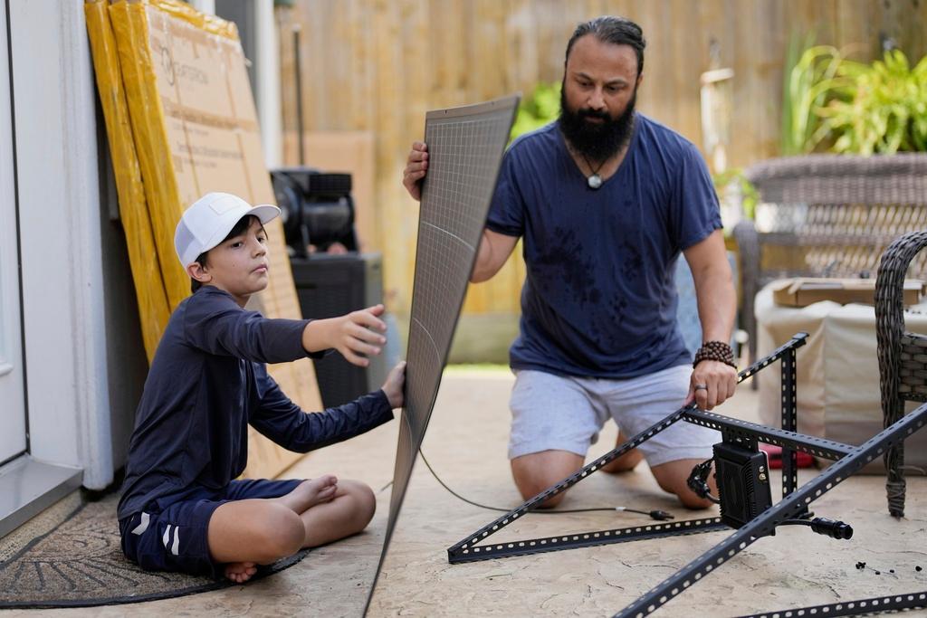 Bhavin Misra, right, and his son, Rumi, 10, assemble a Craftstrom Solar plug-in kit at their home in Houston