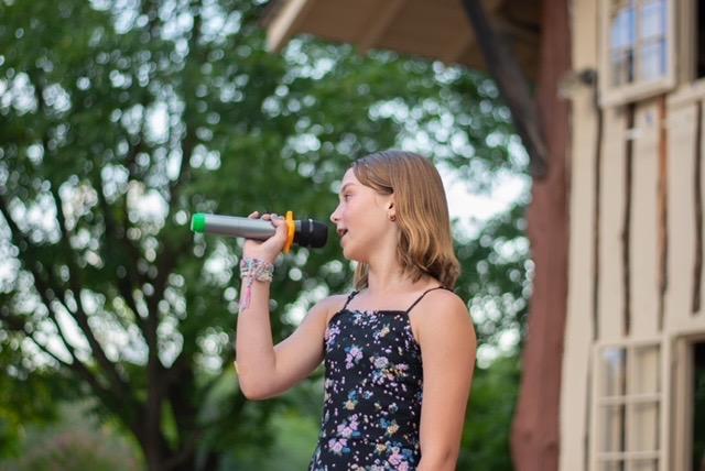 Teen girl with microphone, singing Hallelujah 