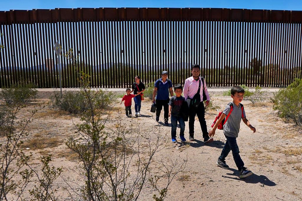 A family of five claiming to be from Guatemala and a man stating he was from Peru, in pink shirt, walk through the desert after crossing the border wall in the Tucson Sector of the U.S.-Mexico border