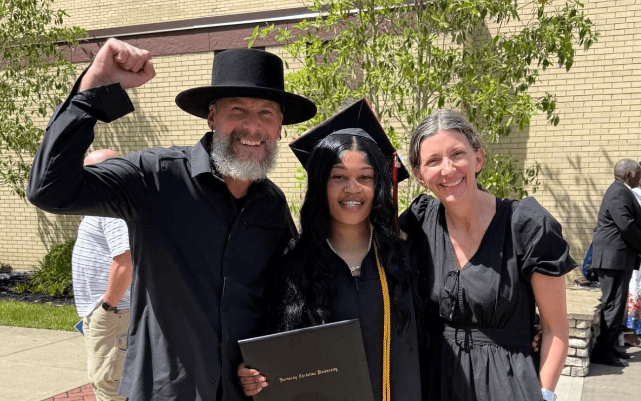 Man with arm up, smiling with a recent college grad, and his wife