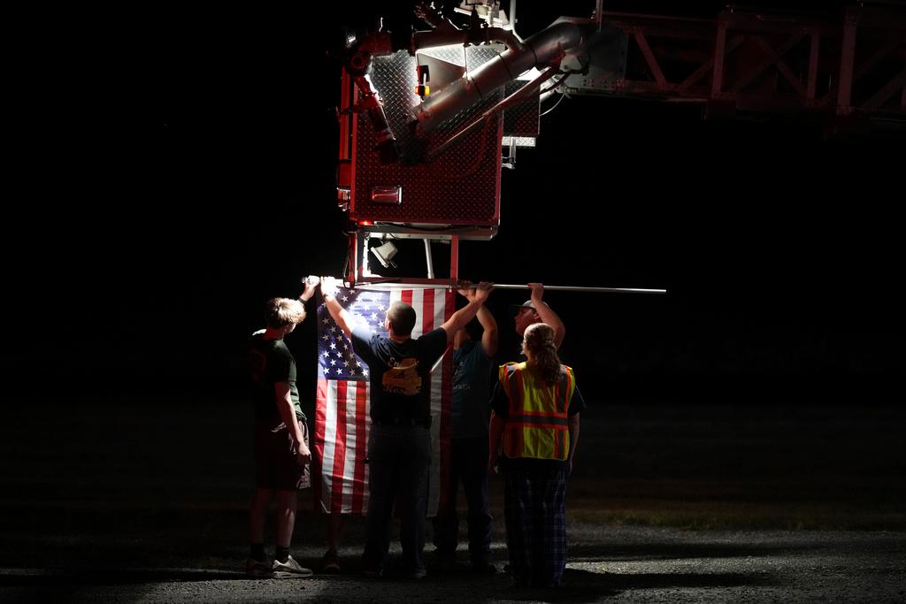 Firefighters attach an American flag to a firetruck before a procession after multiple police officers were shot and killed in Spring Grove, Pa.