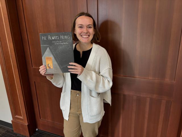 Alyson Punzi holds her first book, "He Always Hears" outside of her office at Cedarville University