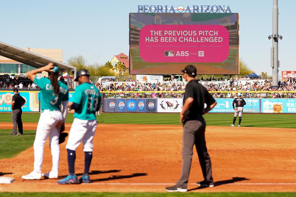 An outfield screen shows a graphic indicating Seattle Mariners' Julio Rodriguez challenged a pitch call, initiating a review with the automated ball-strike challenge system, in the third inning against the Arizona Diamondbacks during a spring training baseball game 