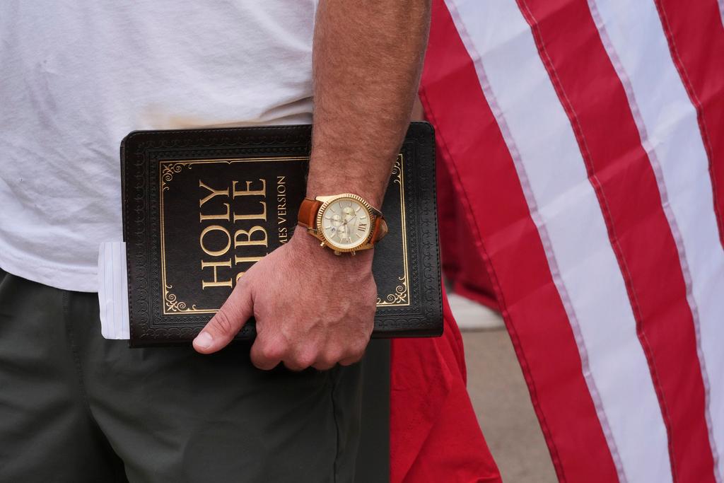 A man holds a Bible outside before a memorial for Charlie Kirk