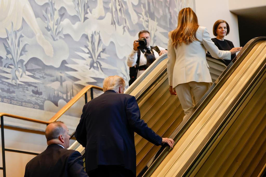 President Donald Trump and First Lady Melania Trump walk up the escalator after it stalled just as he rode up to the General Assembly Hall