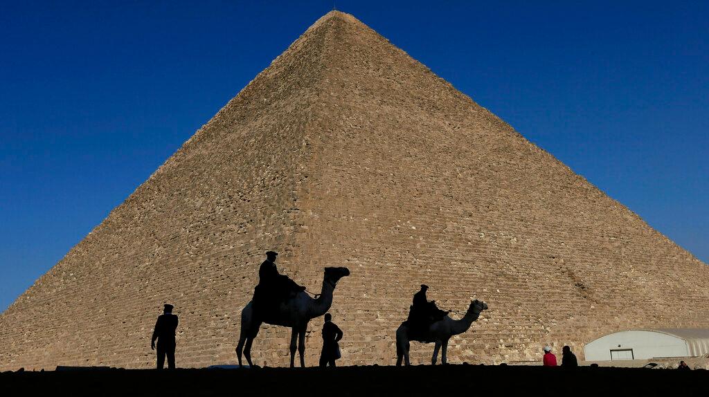Policemen are silhouetted against the Great Pyramid in Giza, Egypt, Dec 12, 2012. Egypt unveiled on Thursday, March 2, 2023, the discovery of a 9-meter-long chamber inside the Great Pyramid of Giza, the first to be found on the structure’s north side.