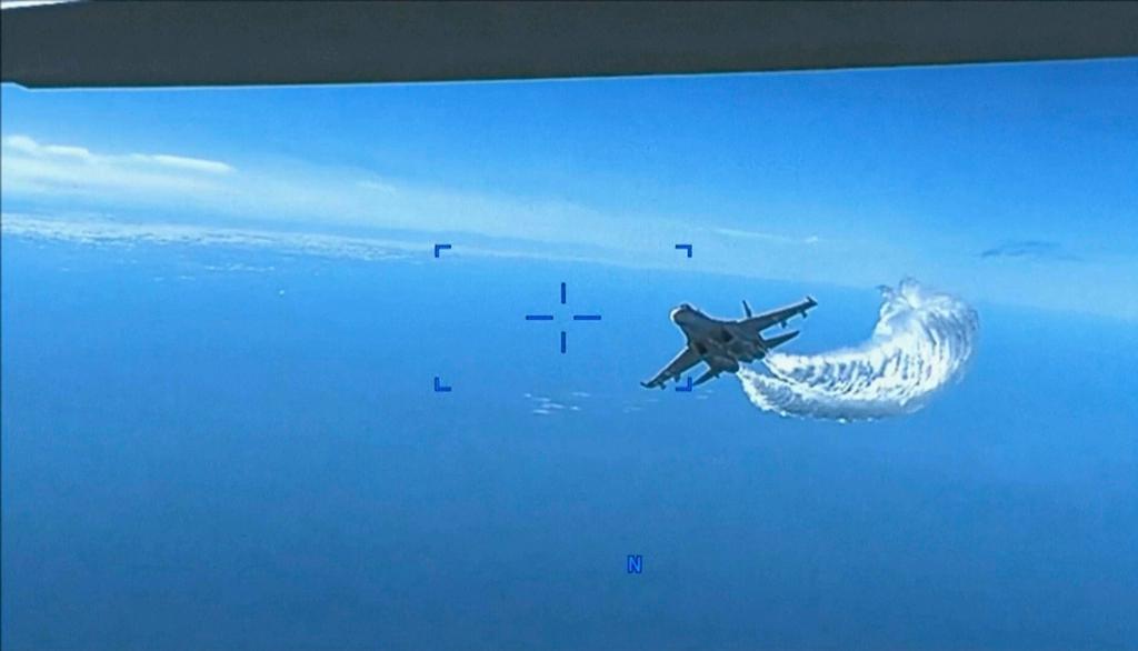 A Russian SU-27 approaching the back of the MQ-9 drone and beginning to release fuel as it passes