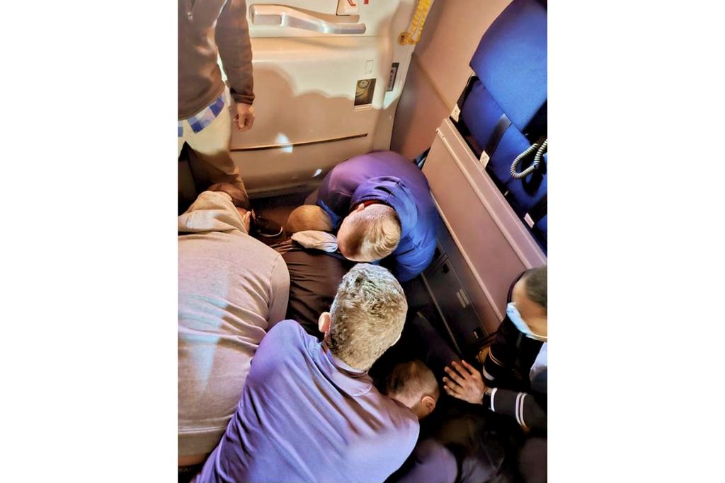 Passengers and crew members restraining a man who according to federal authorities tried to stab a flight attendant on a flight from Los Angeles to Boston