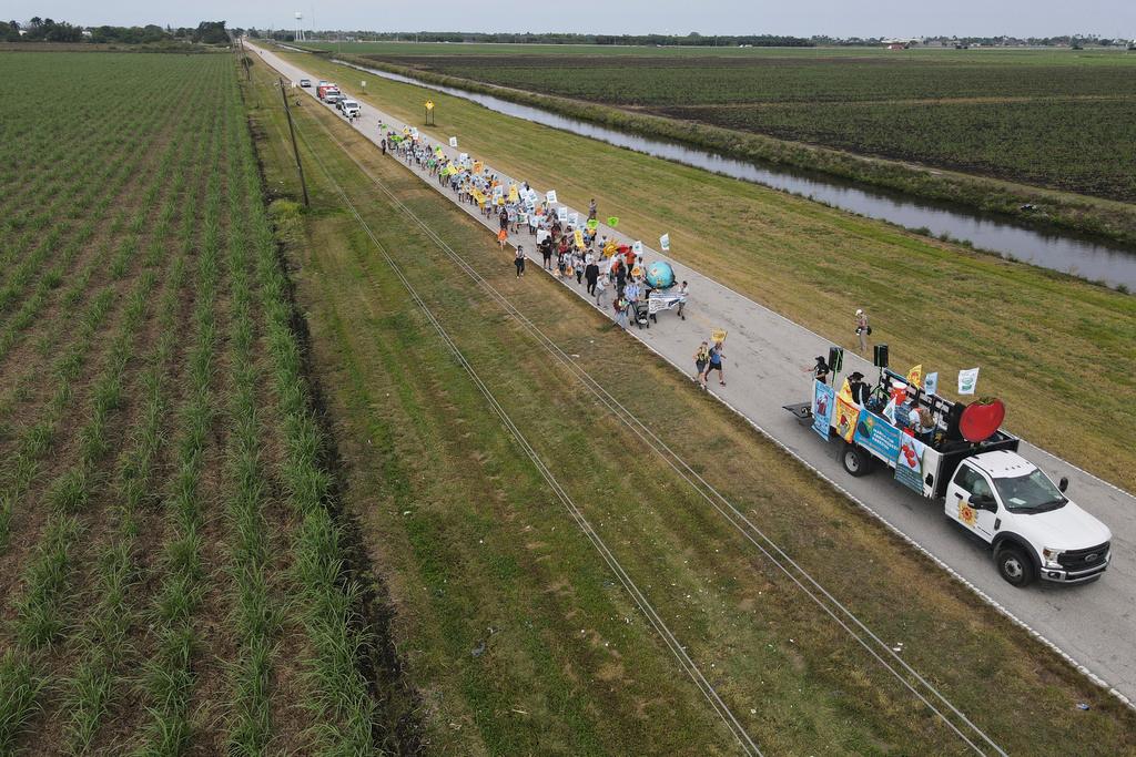In this photo taken with a drone, farmworkers and allies march through agricultural land on the first day of a five-day trek aimed at highlighting the Fair Food Program, which has enlisted food retailers to use their clout with growers to ensure better working conditions and wages for farmworkers, Tuesday, March 14, 2023, in Pahokee, Fla.